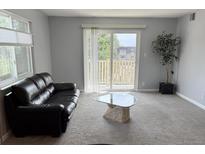 Bright living room with a sliding glass door leading to a balcony and comfortable seating at 7495 E Quincy Ave # 205, Denver, CO 80237