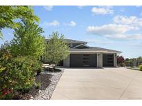 Beautiful home featuring a stone exterior, three-car garage, and a wide driveway surrounded by lush greenery at 14712 Kalamath Ct, Westminster, CO 80023