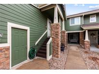 Green townhome exterior with stone accents, private entrance, and well-maintained walkway at 19437 E Mann Creek Dr # A, Parker, CO 80134