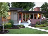 Charming single-story home featuring a brick accent wall, well-maintained lawn, and vibrant flower beds at 8955 E 19Th Ave, Aurora, CO 80010