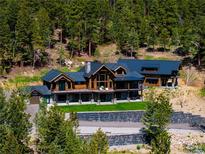 Beautiful mountain home featuring natural wood construction and a lovely stone retaining wall and professional landscaping at 534 W Meadow Rd, Evergreen, CO 80439