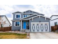 Charming two-story home featuring a bright blue front door and a stylish garage with white cross design at 605 Wild Honey Dr, Berthoud, CO 80513