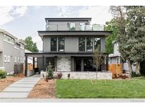 Stunning three-story home with a stone facade, modern wood siding, and rooftop terrace with glass railing at 1665 S Fillmore St, Denver, CO 80210