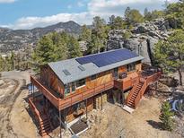 Stunning mountain home featuring a wraparound deck and solar panels, blending rustic charm with modern sustainability at 31911 Warrens Rd, Golden, CO 80403