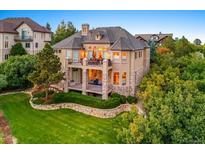 Spacious backyard featuring a large deck, stone accents, and lush landscaping at 1222 Buffalo Ridge Rd, Castle Pines, CO 80108