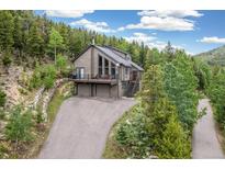 Mountain home features a deck, offering stunning views of the surrounding forest and hillside at 1758 Sinton Rd, Evergreen, CO 80439
