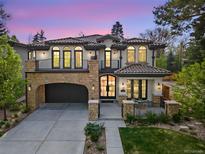 Elegant home with a stone archway garage, charming balconies, and manicured lawn at 455 Forest St, Denver, CO 80220