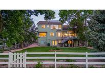 Spacious backyard with lush lawn, mature trees, large deck, and white picket fence at 6266 Holman St, Arvada, CO 80004
