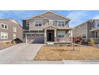 Two-story home featuring a covered front porch, a two-car garage, and neutral-tone siding at 14800 Hudson St, Thornton, CO 80602