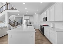 Bright kitchen boasts stainless appliances, white cabinets, and a large center island at 14800 Hudson St, Thornton, CO 80602