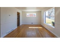 Bright living room with hardwood floors and lots of natural light from the large windows at 10454 Grant Dr, Northglenn, CO 80233