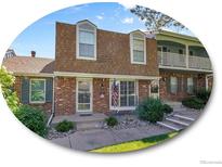 Charming brick townhome featuring a well-maintained lawn and a welcoming entrance with an American flag at 7391 S Knolls Way, Centennial, CO 80122