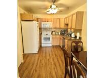 Traditional kitchen featuring wood cabinets, white appliances, and laminate flooring at 635 S Alton Way # 1B, Denver, CO 80247