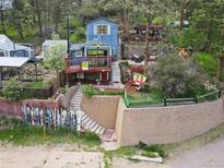 Charming blue two-story home with a deck and landscaped yard on a hillside at 27383 Highway 74, Evergreen, CO 80439