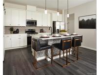 Modern kitchen boasts white cabinets, stainless steel appliances, pendant lighting, and an island with bar stool seating at 6153 N Ceylon St # 305, Denver, CO 80249
