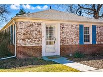 Charming brick home featuring a storm door entrance, blue shutters, and a well-maintained front lawn at 1257 Locust St, Denver, CO 80220