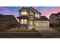 Two-story home featuring a well-maintained lawn, front porch, and a two-car garage with brick accents at 13475 Spruce St, Thornton, CO 80602
