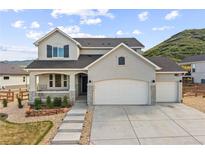 Charming two-story home with a three car garage and landscaped front yard nestled against a picturesque hillside at 5446 Mesa Top Dr, Monument, CO 80132