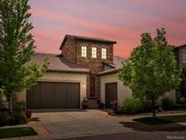 Charming stucco two-story home with a tiled roof, stone accents, mature landscaping, and a two-car garage at 15264 W La Salle Ave, Lakewood, CO 80228