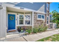 Charming townhome entrance features a blue door, stone accents, and well-maintained landscaping at 23413 E Dorado Pl # A, Aurora, CO 80016