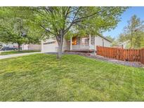 Charming home with a lush green lawn, a two-car garage and a quaint front porch at 16179 W 70Th Pl, Arvada, CO 80007