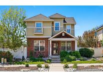 Charming two-story home featuring a brick facade, well-maintained landscaping, and a welcoming front porch at 1063 Roslyn Ct, Denver, CO 80230