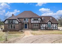 Charming two-story home with a brick and tudor exterior, a blue front door, and a well-manicured front yard at 28800 E 168Th Ave, Brighton, CO 80603