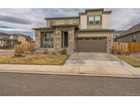 Inviting two-story home with a stone facade, a two-car garage, and a cozy front porch, perfect for relaxing at 13329 Newport Cir, Thornton, CO 80602