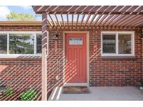 Charming brick home featuring a vibrant coral front door and a stylish pergola entrance at 3316 N Glencoe St, Denver, CO 80207