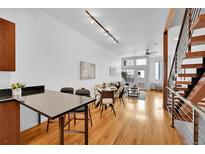 Bright open-concept living room featuring hardwood floors, modern lighting, and a dining area with a staircase at 2680 Blake St # 13, Denver, CO 80205