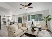 Bright living room with modern ceiling fan, large windows, and view of kitchen and dining area at 21486 E Crestline Ln, Centennial, CO 80015