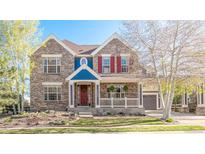 Charming two-story home featuring a lovely front porch, brick facade, and colorful details at 17294 W 60Th Ct, Arvada, CO 80403