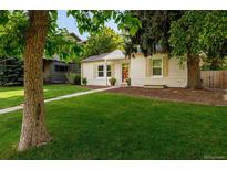 Charming single story home with a well manicured front lawn, framed by mature trees and a tidy walkway at 3047 N Milwaukee St, Denver, CO 80205