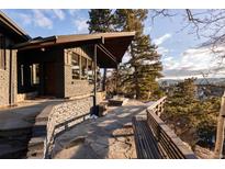 Modern home featuring a stone patio with wooden benches and mountain views at 22598 Westview Ave, Golden, CO 80401