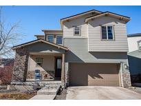 Inviting two-story home featuring a covered porch with stone accents and a two car garage at 162 Starlight Cir, Erie, CO 80516