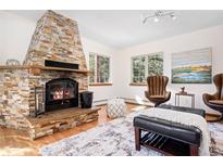 Inviting living room showcasing a stone fireplace, hardwood floors and natural light from two windows overlooking the outdoors at 439 Ronnie Rd, Golden, CO 80403
