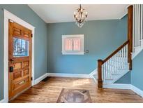 Inviting entryway with hardwood floors, decorative chandelier, and wooden staircase at 1006 S Emerson St, Denver, CO 80209