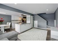 Open concept living room and kitchen with wood floors and a white shag rug at 1204 S Uvalda St, Aurora, CO 80012