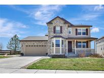 Charming two-story home with stone and tan siding, landscaped yard, and inviting front porch at 22268 E Hidden Trail Dr, Parker, CO 80138