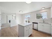 Bright kitchen with white cabinets, stainless appliances, and a central island with quartz countertops at 4965 Collinsville Pl, Highlands Ranch, CO 80130