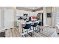 Modern kitchen boasts white cabinets, stainless steel appliances and a center island with seating at 3297 N Duquesne Way, Aurora, CO 80019