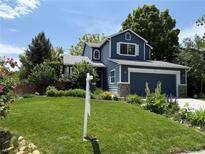 Charming blue two-story home featuring a manicured lawn and inviting curb appeal at 823 Timothy Dr, Longmont, CO 80503