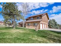Charming two-story home boasts a brick facade, three-car garage, and a lush green lawn under a sunny sky at 9745 Derby Way, Parker, CO 80134