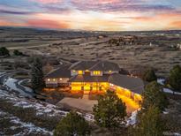 Stunning multi-story home with a three-car garage and warm lighting at dusk at 6204 Hay Meadow Way, Sedalia, CO 80135