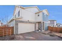 Charming two-story home featuring stone accents, an attached two-car garage, and a well-maintained brick driveway at 10207 Xanadu St, Commerce City, CO 80022