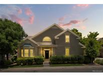 Charming home showcasing lush landscaping, gray siding, gabled roof, and a well-manicured lawn at dusk at 4545 S Monaco St # 114, Denver, CO 80237