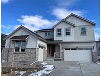 Charming two-story home with stone accents, a red front door, and a three-car garage on a sunny day at 651 Sunrise St, Erie, CO 80516