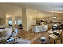 Bright and open-concept living space featuring hardwood floors, a kitchen island, and comfortable seating at 5554 S Ward Way, Littleton, CO 80127