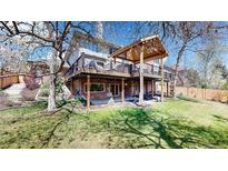 Expansive backyard featuring a covered deck, lush lawn, and mature trees creating an inviting outdoor living space at 10346 E Crestridge Ln, Englewood, CO 80111