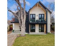 Stunning modern home with a white brick facade, black accents, balcony, and professionally landscaped yard at 1675 S Steele St, Denver, CO 80210